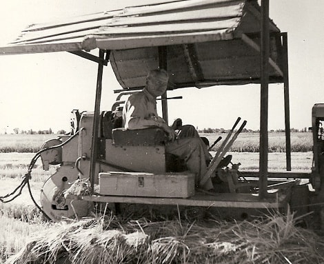 Old black and white image of a man using an antique tractor
